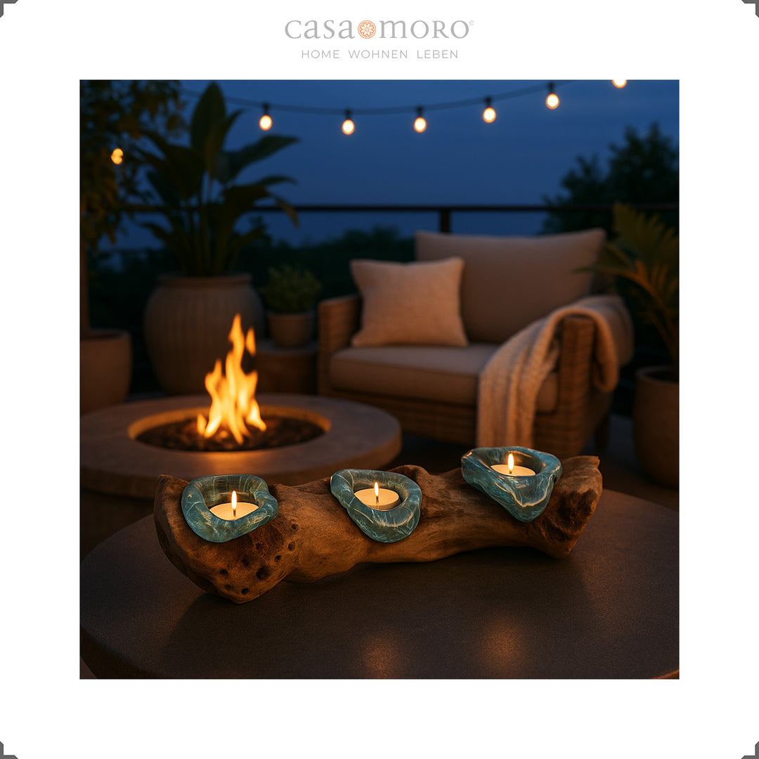 Portavelas de vidro e madeira de raiz numa esplanada ao anoitecer, rodeadas por uma lareira e decoração boho para exterior