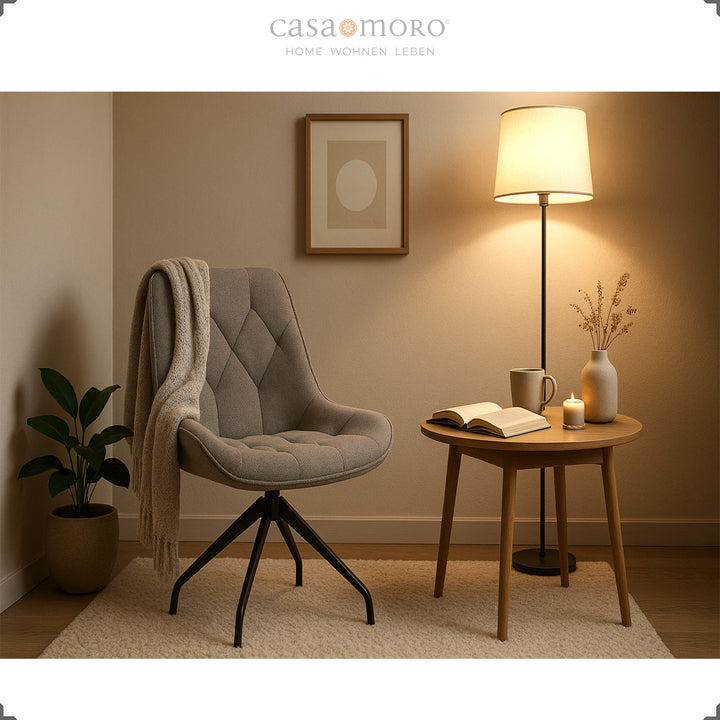 Cadeira de sala de jantar cinzenta com rotação de 360° e estrutura em metal preto – recanto de leitura acolhedor com mesa de apoio, manta e luz quente