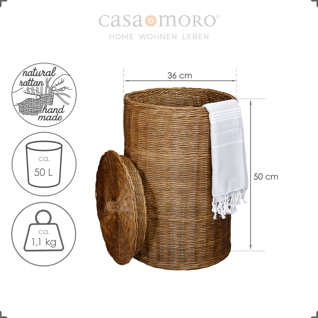 Cesto de rattan castanho-escuro com tampa e toalha de banho clara, com cerca de 50 cm de altura, entrançado à mão com material natural