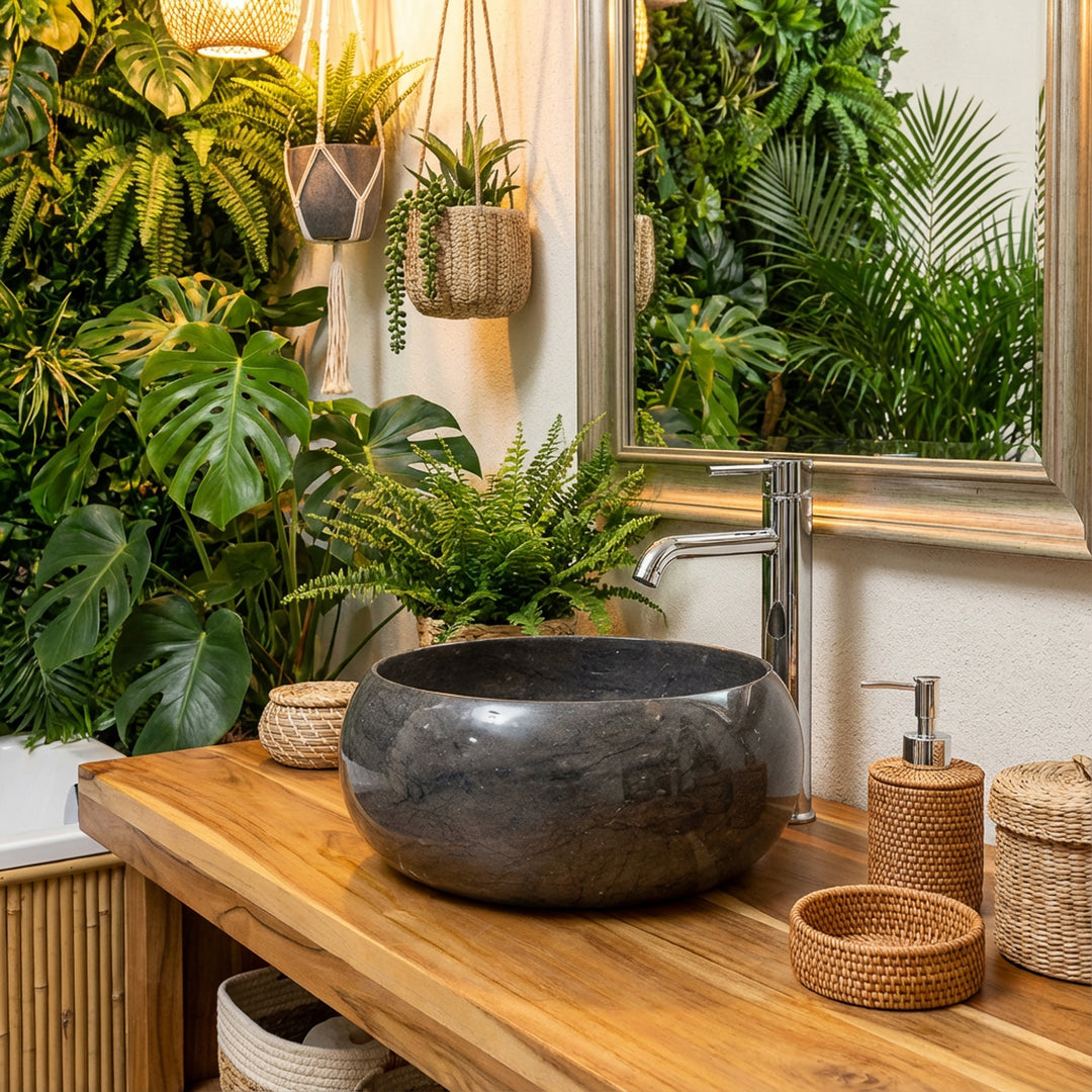 Lavatório redondo em pedra sobre um móvel de madeira, numa casa de banho tipo spa com tons verdes, parede vegetal, espelho e iluminação acolhedora