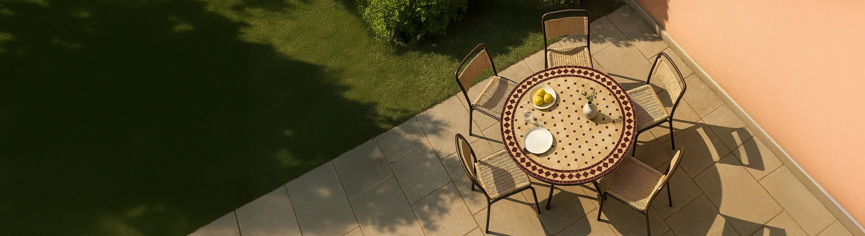 Mesas em mosaico Ø100 – Großer runder Mosaiktisch Ø100 cm mit Zellige-Fliesen und mehreren Stühlen auf Terrasse im Garten aus der Vogelperspektive mit warmem Sonnen