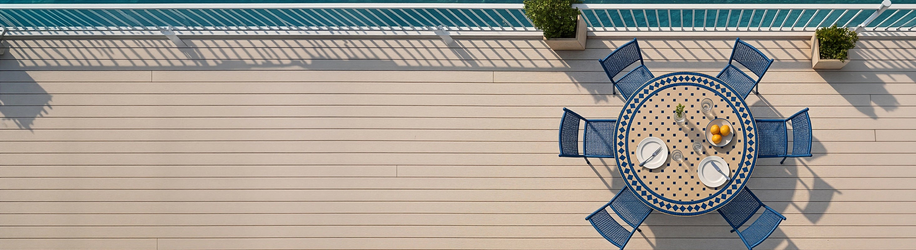Mesas em mosaico Ø120 – Grande mesa redonda de mosaico Ø120 cm com azulejos zellige azuis e várias cadeiras vista aérea no terraço com vista mar