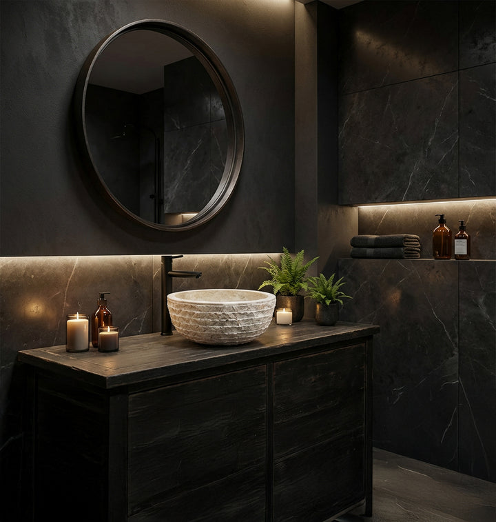 Lavatório elegante em pedra natural, montado sobre uma bancada escura, numa moderna casa de banho tipo spa à luz de velas