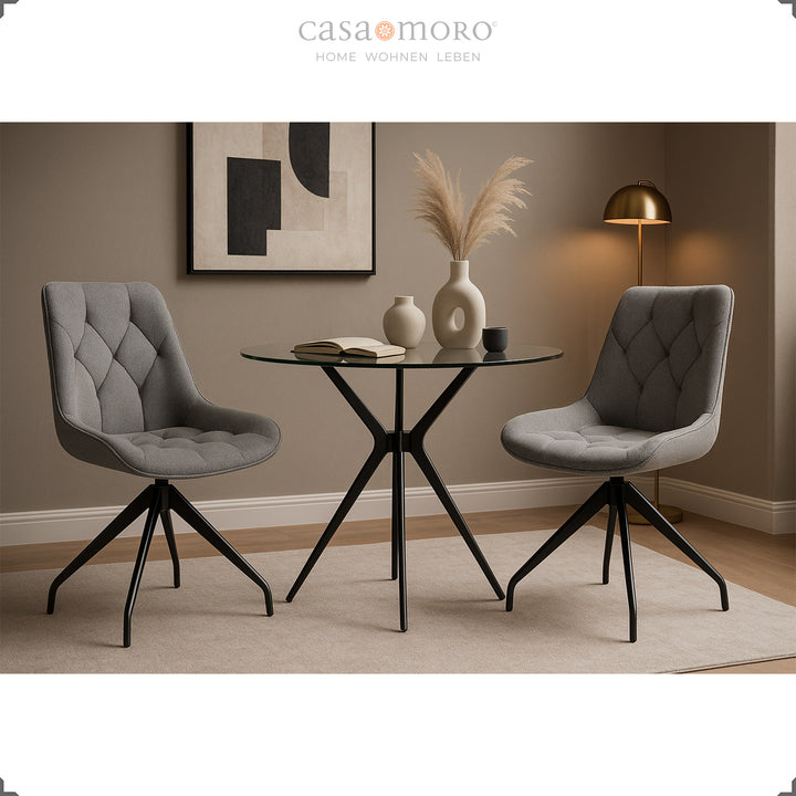 Duas cadeiras de sala de jantar cinzentas com rotação de 360° e estrutura em metal preto – conjunto de cadeiras elegante com mesa de vidro e ambiente de iluminação acolhedora
