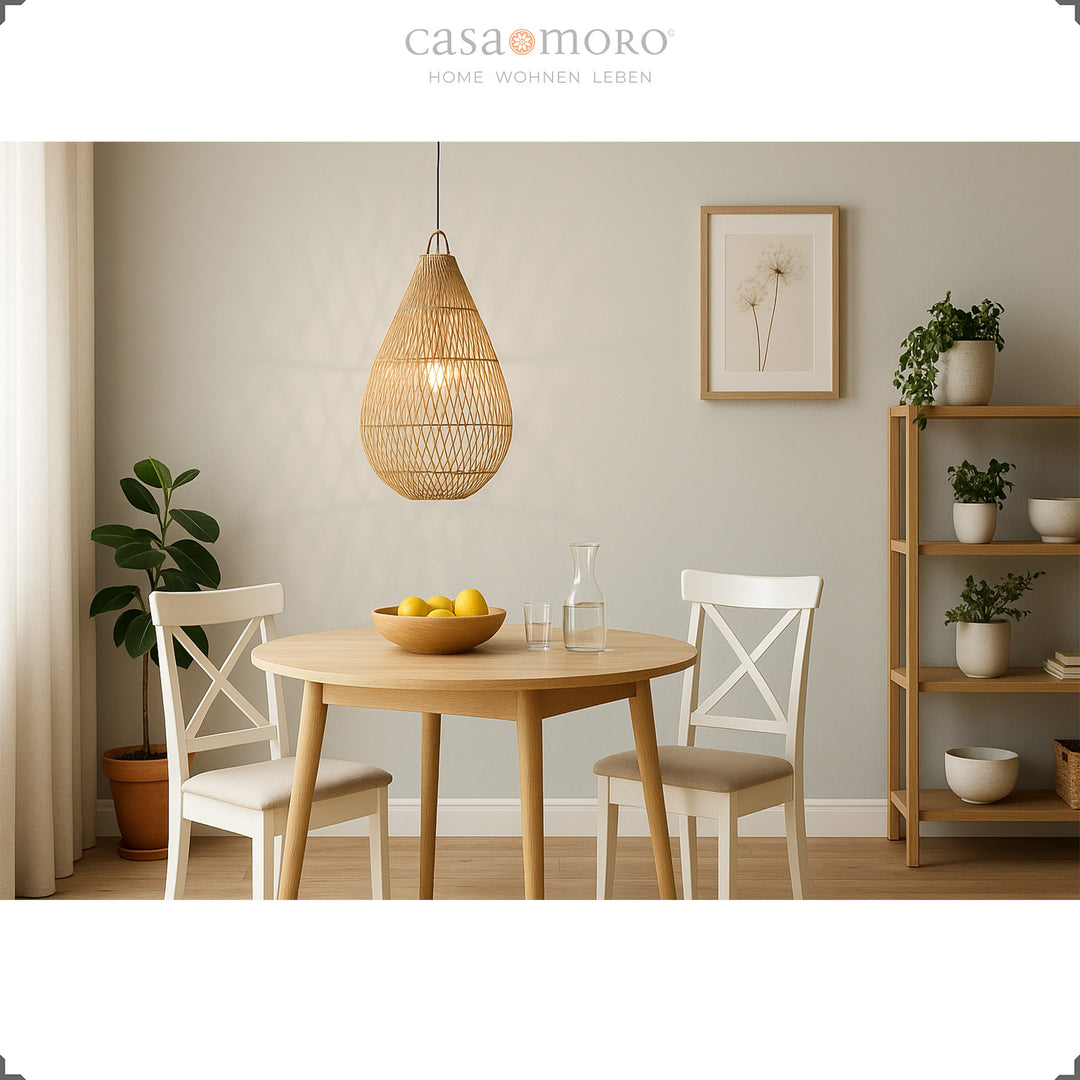 Candeeiro de rattan feito à mão em forma de gota, suspenso sobre uma mesa de jantar, que emana uma luz acolhedora e cria um ambiente acolhedor