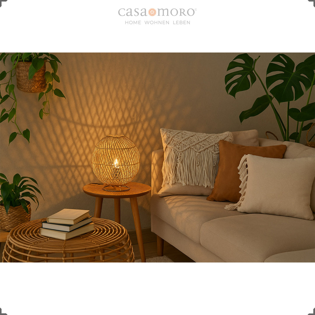 Candeeiro redondo de vime sobre uma mesinha de apoio numa acolhedora sala de estar com um recanto de sofás e luz acolhedora