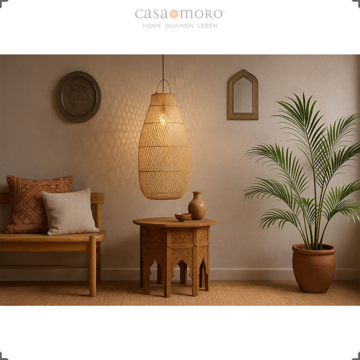 Grande candeeiro de vime sobre uma mesa oriental na sala de estar, com luz quente e tons naturais