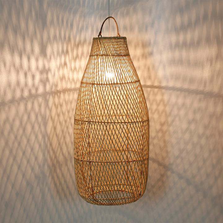 Candeeiro alto de rattan com um delicado padrão de trançado e um jogo de luzes acolhedoras na parede
