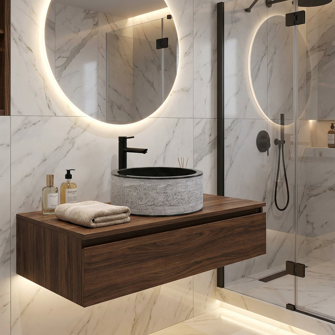 Lavatório redondo em pedra sobre uma consola suspensa em madeira, combinado de forma moderna com torneiras pretas numa casa de banho de design elegante.