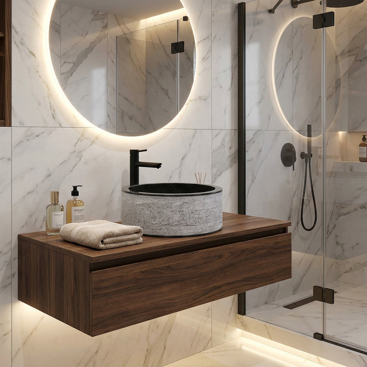 Lavatório redondo em pedra sobre uma consola suspensa em madeira, combinado de forma moderna com torneiras pretas numa casa de banho de design elegante.