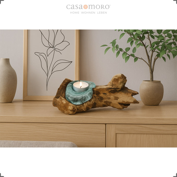 Um castiçal de vidro e madeira de raiz sobre um aparador; a sua luz acolhedora complementa a decoração natural e simples da sala de estar.
