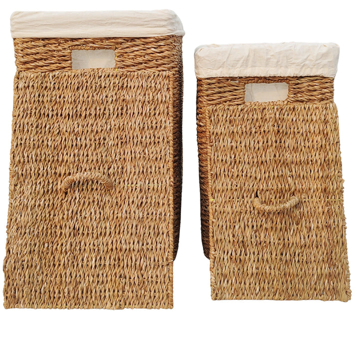 Dois cestos para roupa suja em erva-do-mar, com capacidades de 50 e 90 litros, com inserções em tecido claro e tampas encostadas à frente, dotadas de pegas.