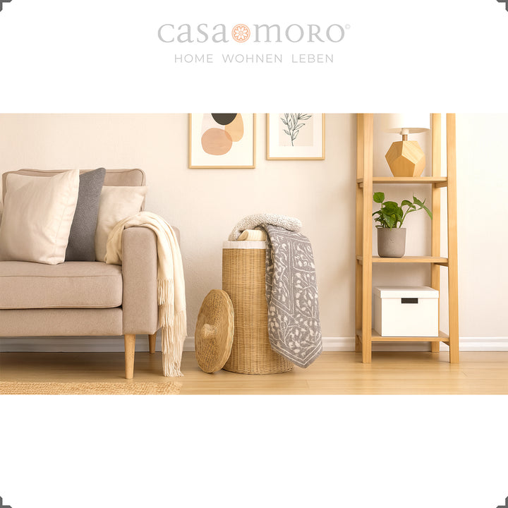 Cesto de roupa suja em rattan na acolhedora sala de estar, com manta e almofadas, a servir de cesto de arrumação