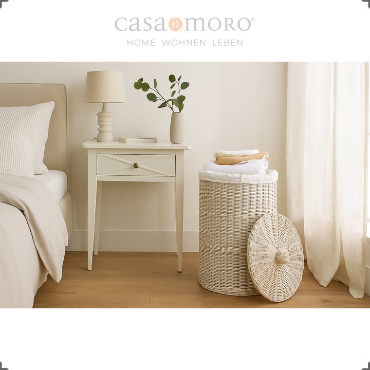 Cesto de roupa suja branco claro no quarto, combinado com tons naturais quentes, cortinas e mesa de cabeceira