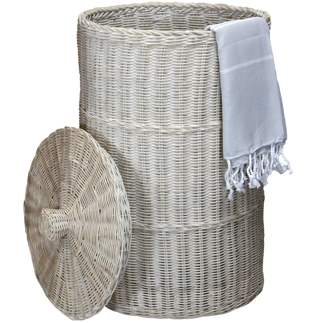 Cesto de roupa suja caiado de branco com um toalhão de banho claro, trançado de forma natural e com um design elegante