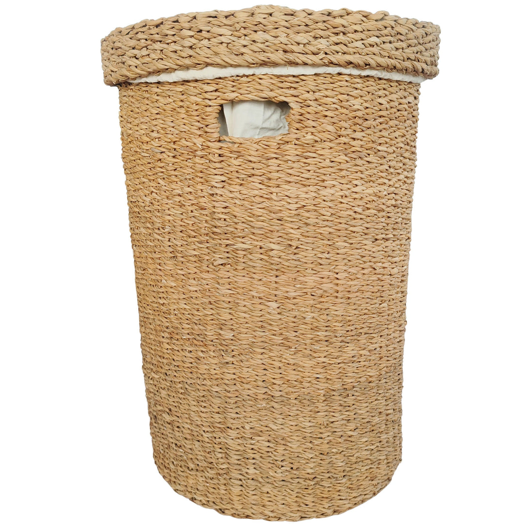 Cesto redondo para roupa suja, feito de algas marinhas, com 75 litros de capacidade, tampa fechada, abertura para pegar e forro em tecido claro.