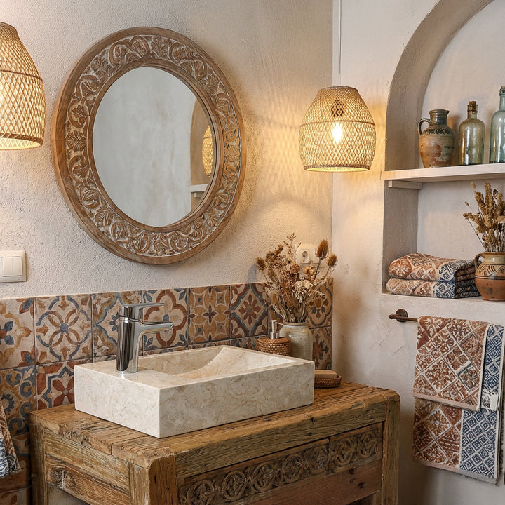 Lavatório retangular de pedra natural clara sobre uma bancada de madeira numa casa de banho de estilo oriental, com azulejos estampados e iluminação acolhedora